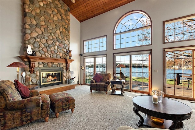 living area with a stone fireplace, wooden ceiling, high vaulted ceiling, carpet floors, and a water view