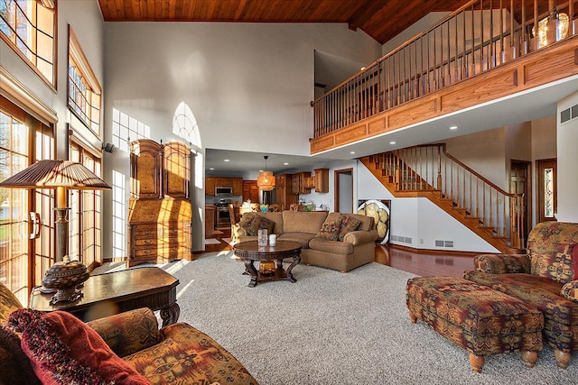 carpeted living room with visible vents, stairs, high vaulted ceiling, and wooden ceiling