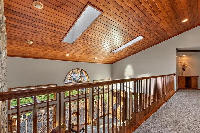 corridor featuring vaulted ceiling with skylight, wooden ceiling, carpet, and recessed lighting