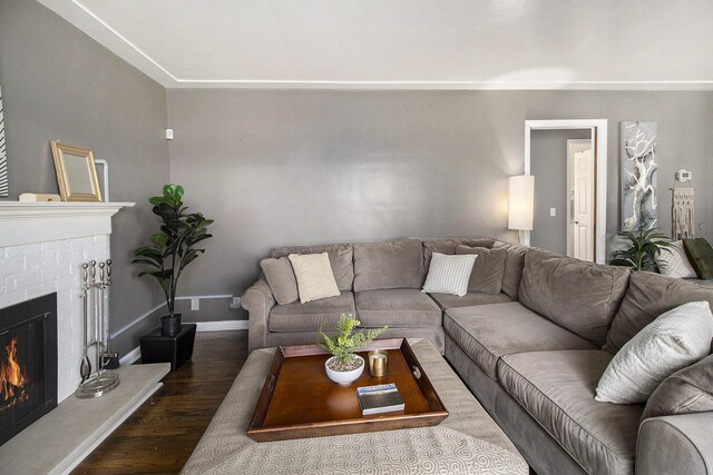 living area featuring baseboards, a brick fireplace, and wood finished floors