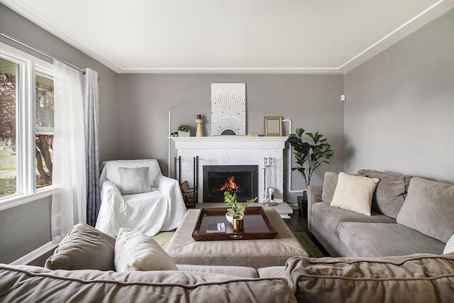 living area featuring baseboards, ornamental molding, a brick fireplace, and wood finished floors