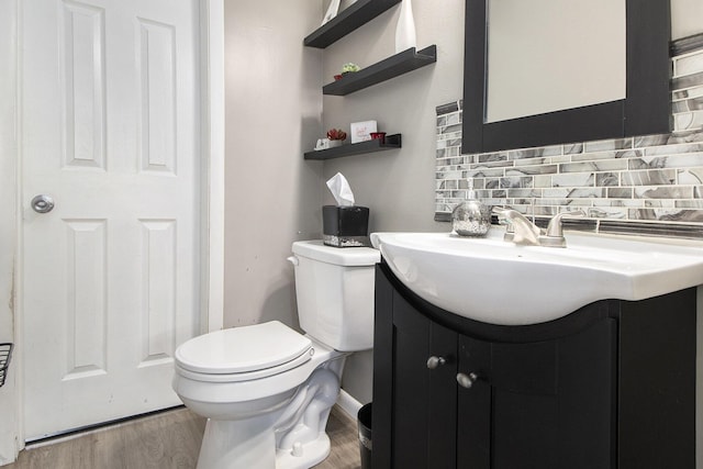 half bath with vanity, decorative backsplash, toilet, and wood finished floors