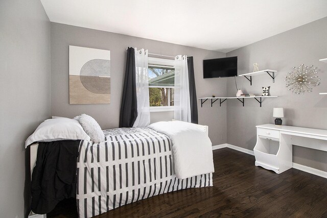 bedroom with dark wood-type flooring and baseboards