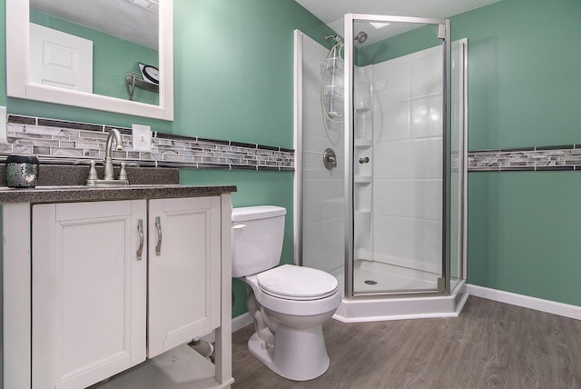 bathroom featuring toilet, a shower stall, wood finished floors, and tasteful backsplash