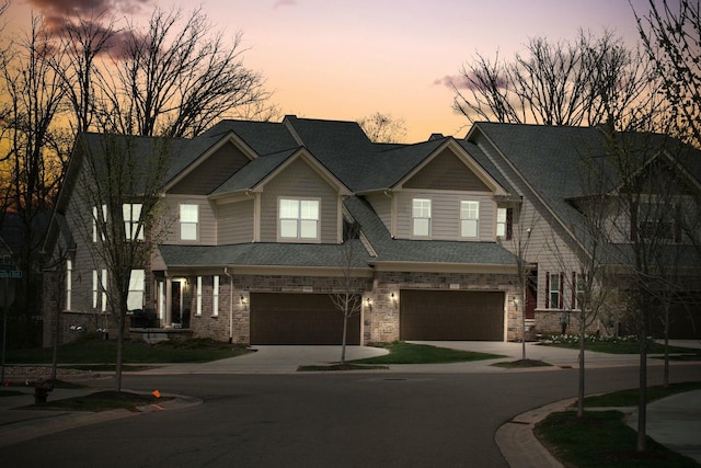 multi unit property featuring concrete driveway, stone siding, a garage, and a shingled roof
