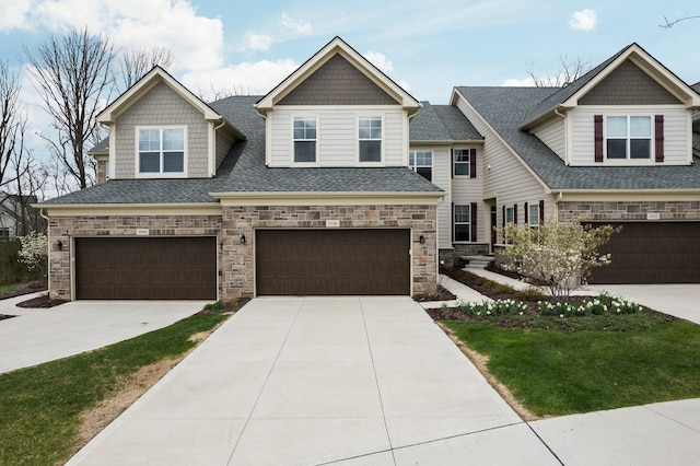 view of front of home featuring a garage, stone siding, roof with shingles, a front lawn, and concrete driveway