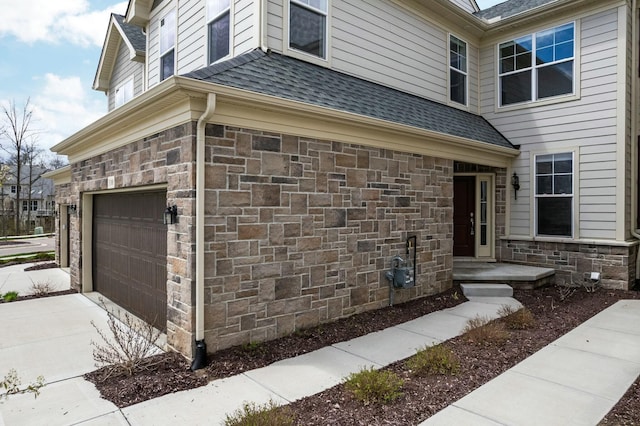 view of home's exterior with a garage, a shingled roof, concrete driveway, and stone siding