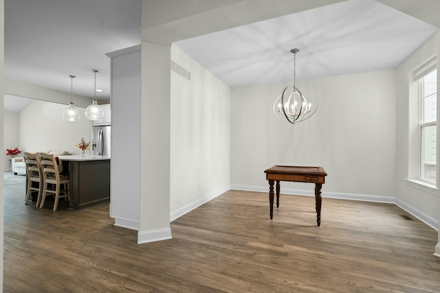unfurnished dining area featuring visible vents, baseboards, a chandelier, and dark wood finished floors