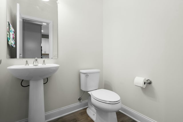 bathroom with toilet, a sink, wood finished floors, and baseboards