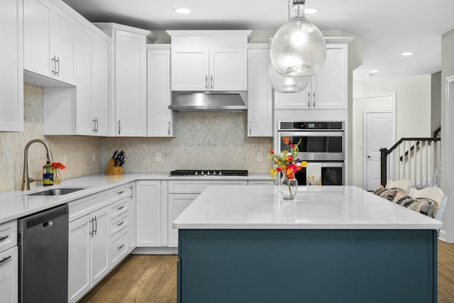 kitchen featuring a sink, under cabinet range hood, dishwashing machine, stainless steel double oven, and gas stovetop