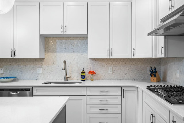 kitchen with a sink, under cabinet range hood, light countertops, white cabinets, and appliances with stainless steel finishes