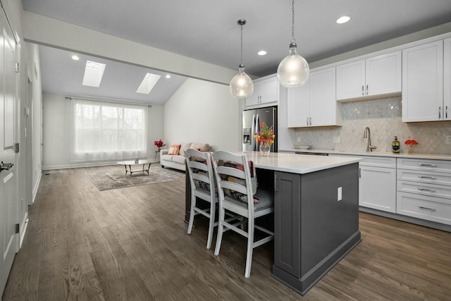 kitchen featuring white cabinetry, a kitchen island, stainless steel fridge, and a sink