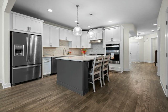 kitchen with appliances with stainless steel finishes, light countertops, white cabinets, and dark wood-style floors