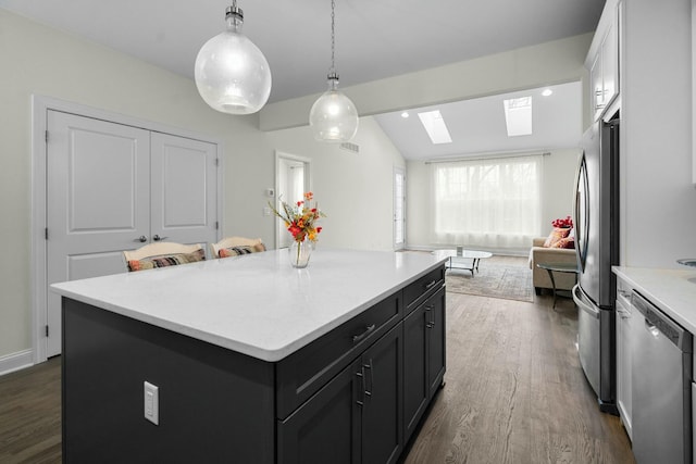 kitchen featuring appliances with stainless steel finishes, dark wood-type flooring, light countertops, and lofted ceiling with skylight