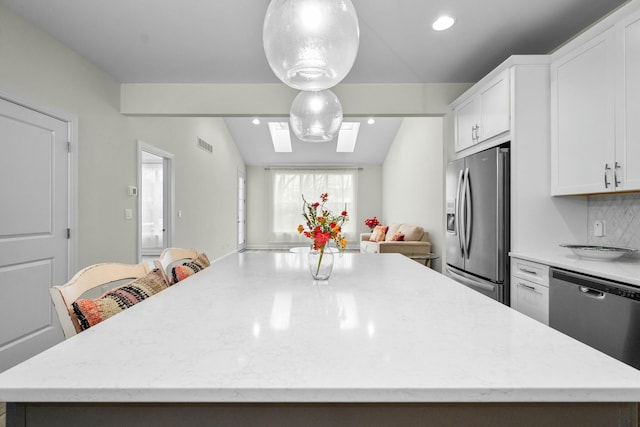 kitchen featuring appliances with stainless steel finishes, white cabinets, a center island, visible vents, and lofted ceiling
