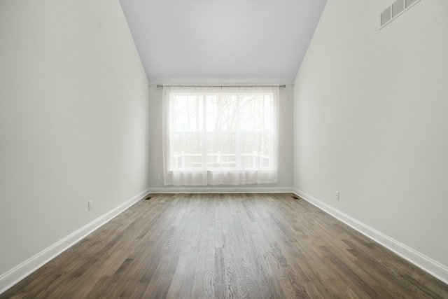 unfurnished room featuring dark wood-style floors, baseboards, visible vents, and lofted ceiling