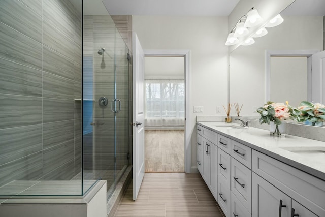bathroom with a shower stall, double vanity, and a sink