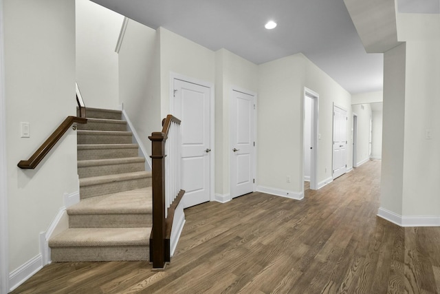 staircase with wood finished floors, recessed lighting, and baseboards