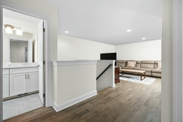 hall featuring a sink, an upstairs landing, baseboards, recessed lighting, and wood finished floors
