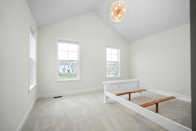 carpeted spare room featuring baseboards, visible vents, a notable chandelier, and vaulted ceiling