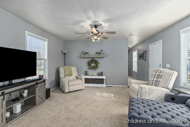 living room with baseboards, a ceiling fan, and light carpet