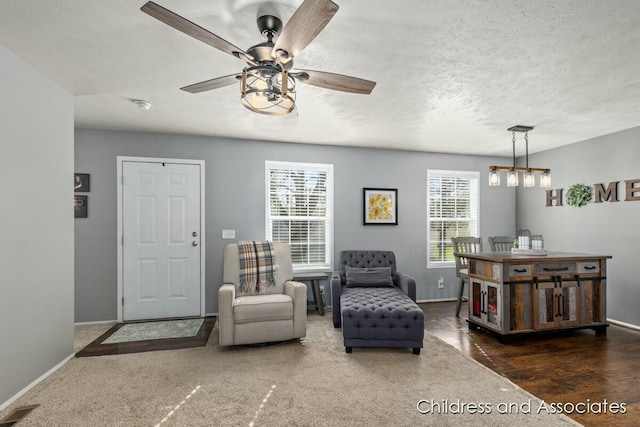 living area with baseboards, a ceiling fan, a textured ceiling, and visible vents