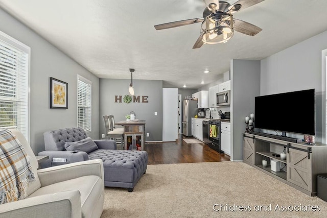 living area featuring dark carpet, baseboards, and ceiling fan