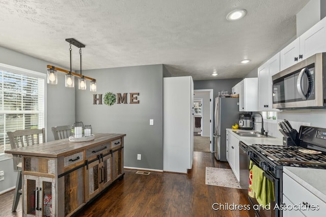 kitchen with dark wood-style flooring, baseboards, white cabinets, a sink, and stainless steel appliances