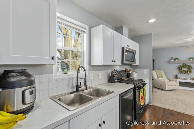 kitchen with a sink, light countertops, black appliances, and white cabinetry