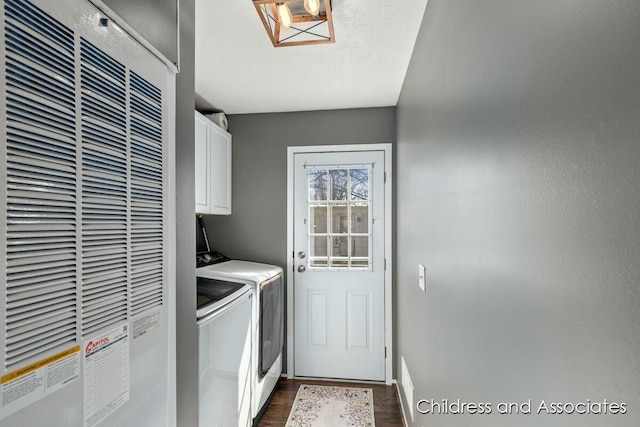 washroom featuring cabinet space, washing machine and clothes dryer, a heating unit, baseboards, and dark wood-type flooring