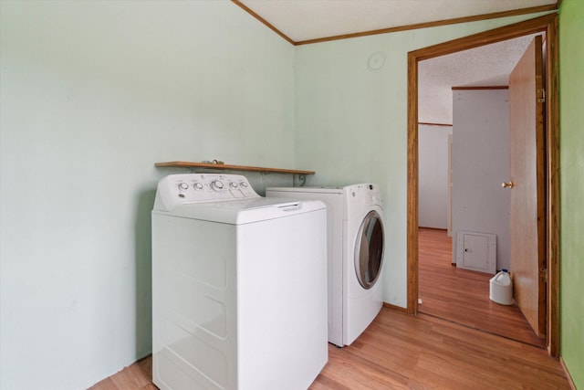 laundry area with ornamental molding, laundry area, light wood finished floors, and washer and dryer
