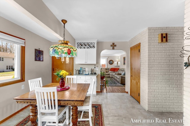 dining space featuring a healthy amount of sunlight, brick wall, and arched walkways