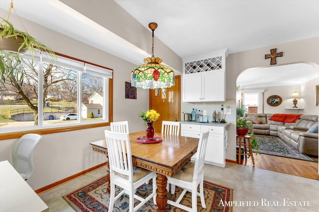dining room with a healthy amount of sunlight, baseboards, and arched walkways
