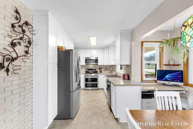 kitchen with white cabinetry, stainless steel appliances, light countertops, and a sink