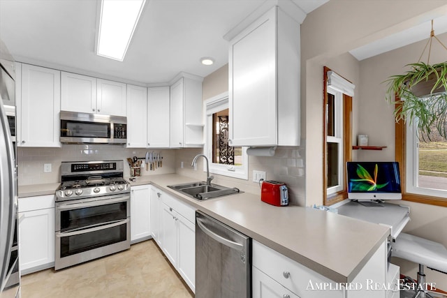 kitchen with appliances with stainless steel finishes, light countertops, and a sink