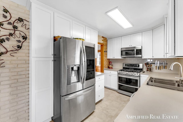 kitchen featuring a sink, white cabinets, stainless steel appliances, and light countertops