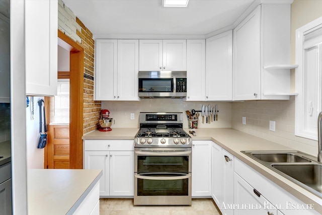 kitchen with a sink, backsplash, stainless steel appliances, and white cabinetry