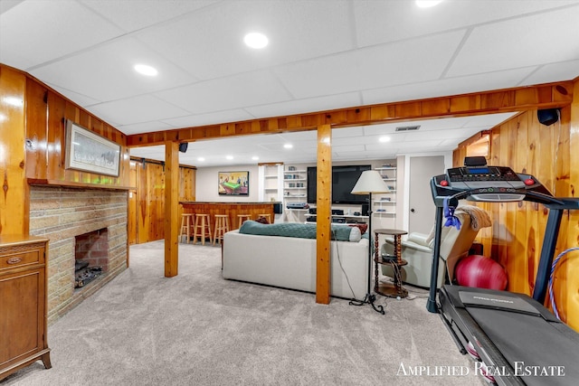 living area with visible vents, wood walls, light carpet, and a brick fireplace