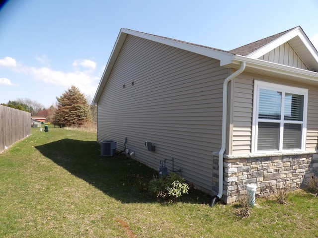 view of side of property featuring a yard, central AC unit, board and batten siding, and stone siding