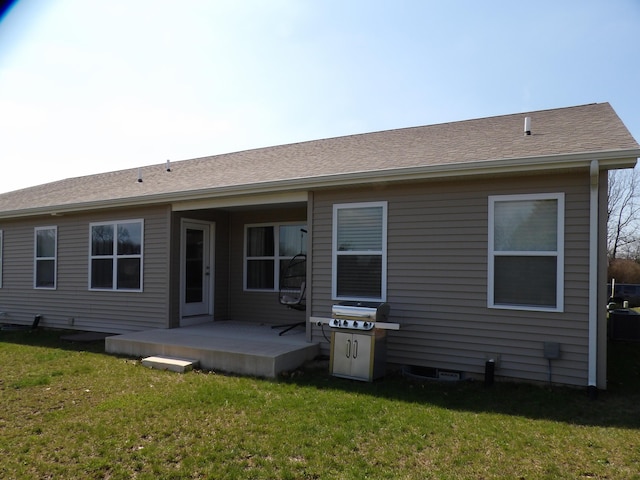 back of house featuring roof with shingles and a yard