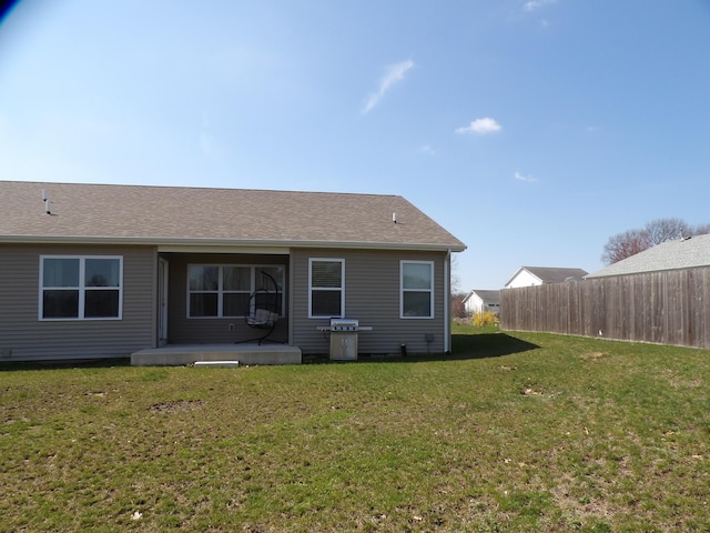 rear view of property featuring a yard and fence