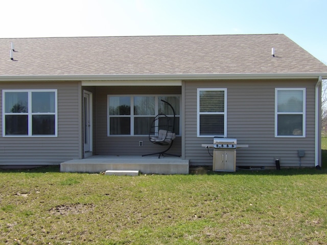 back of property featuring roof with shingles and a yard