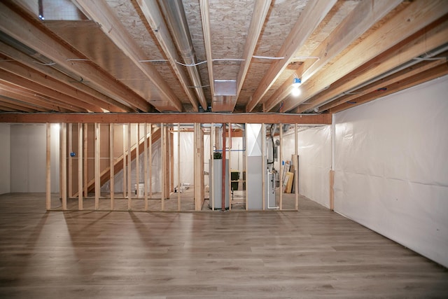 unfinished basement featuring water heater and wood finished floors