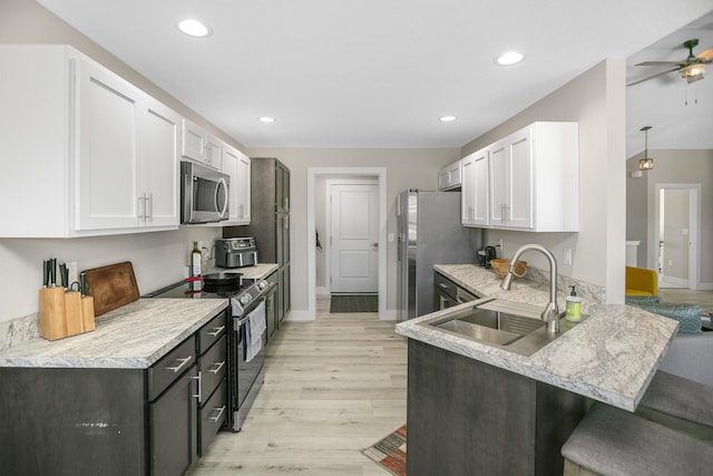 kitchen with light wood-type flooring, a sink, appliances with stainless steel finishes, and white cabinetry