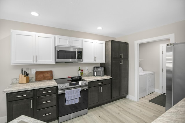 kitchen with white cabinetry, washing machine and clothes dryer, appliances with stainless steel finishes, baseboards, and light wood finished floors