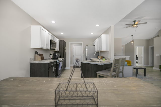 kitchen featuring white cabinetry, a sink, appliances with stainless steel finishes, ceiling fan, and light wood finished floors