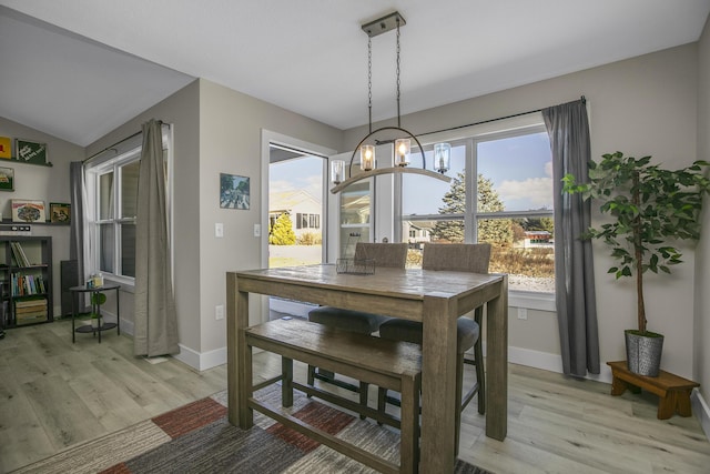 dining area with light wood-type flooring, a notable chandelier, and plenty of natural light