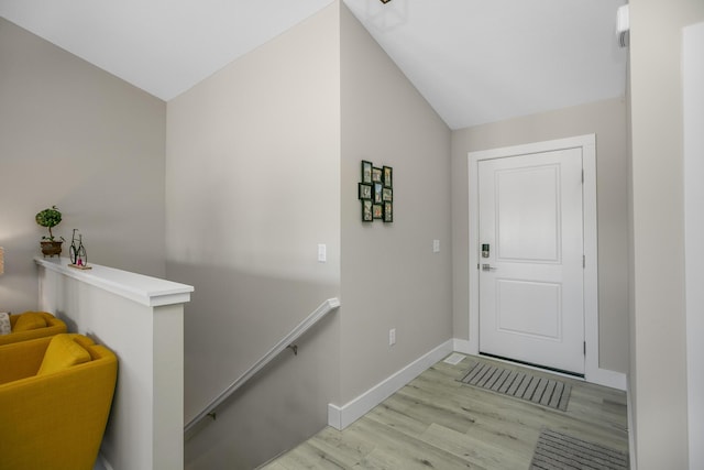 doorway featuring baseboards, wood finished floors, and lofted ceiling