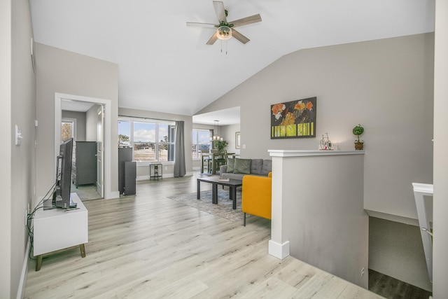 interior space featuring baseboards, vaulted ceiling, wood finished floors, and ceiling fan with notable chandelier