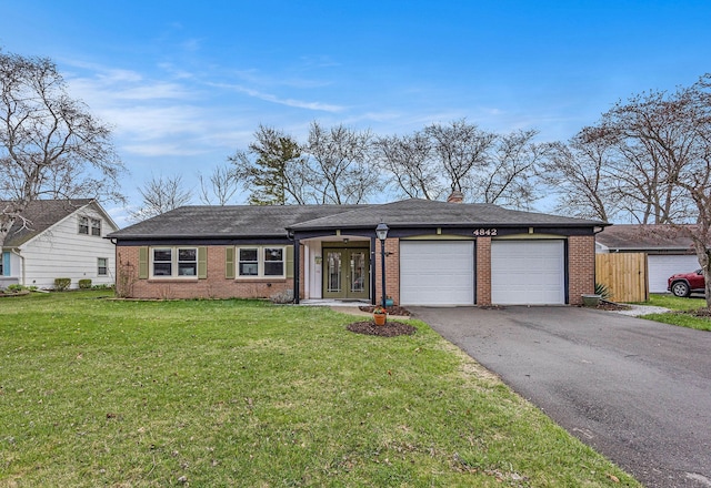 single story home with a front lawn, brick siding, a garage, aphalt driveway, and french doors